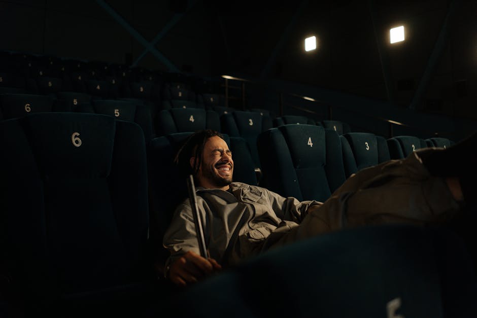 A man smiling while sitting in an empty movie theater, creating a cozy atmosphere.