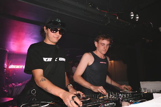 Two DJs mixing tracks at a music club event, creating an energetic atmosphere.